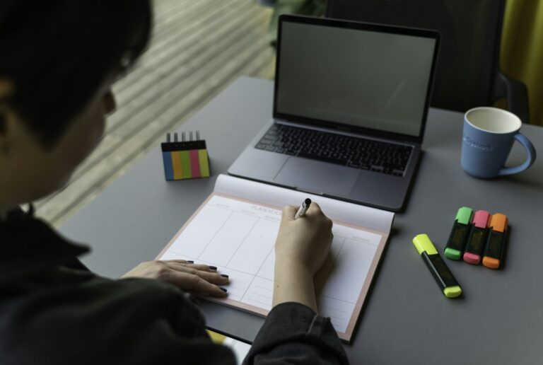 Bitesolgemokz – Person macht sich Notizen neben einem aufgeklappten Laptop