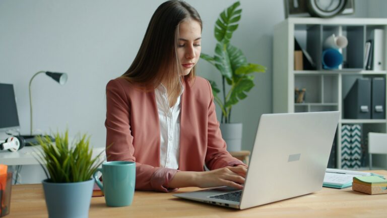 DeepL Write: Was der KI-Schreibassistent kann und was er kostet DeepL Write – Frau schreibt im Büro einen Text am Laptop
