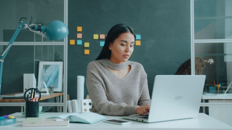 dllhost.exe – Frau arbeitet im Büro an einem aufgeklappten Laptop