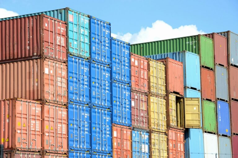 Docker einfach erklärt: Container, Images und Compose verstehen Docker einfach erklärt – gestapelte bunte Frachtcontainer vor blauem Himmel