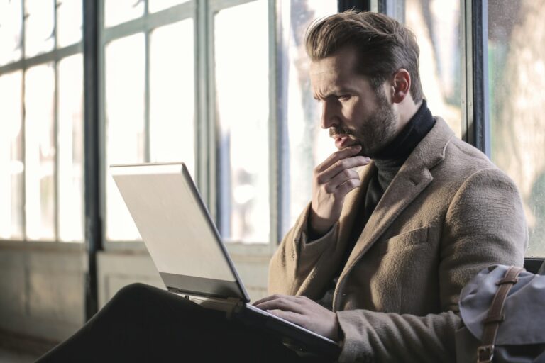 esoszifediv – Mann prüft nachdenklich Informationen auf seinem Laptop
