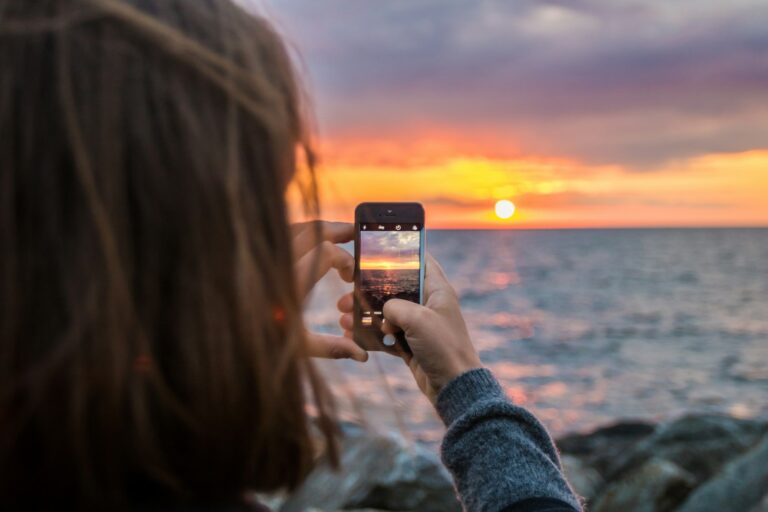 iCloud-Speicher voll? Was passiert und wie du Platz schaffst iCloud Speicher voll – Frau fotografiert mit dem Smartphone einen Sonnenuntergang am Meer