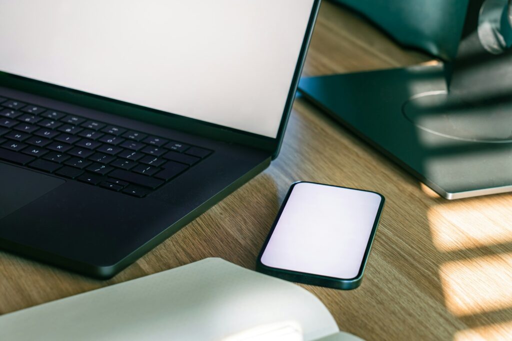 Laptop und Smartphone nebeneinander auf einem Holzschreibtisch, bereit für ein lokales Backup