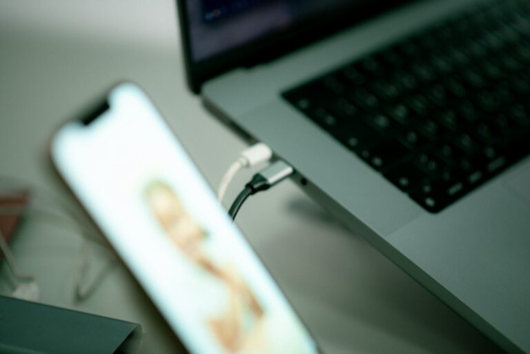 iPhone-Backup auf PC – Smartphone neben einem Laptop mit eingestecktem USB-Kabel
