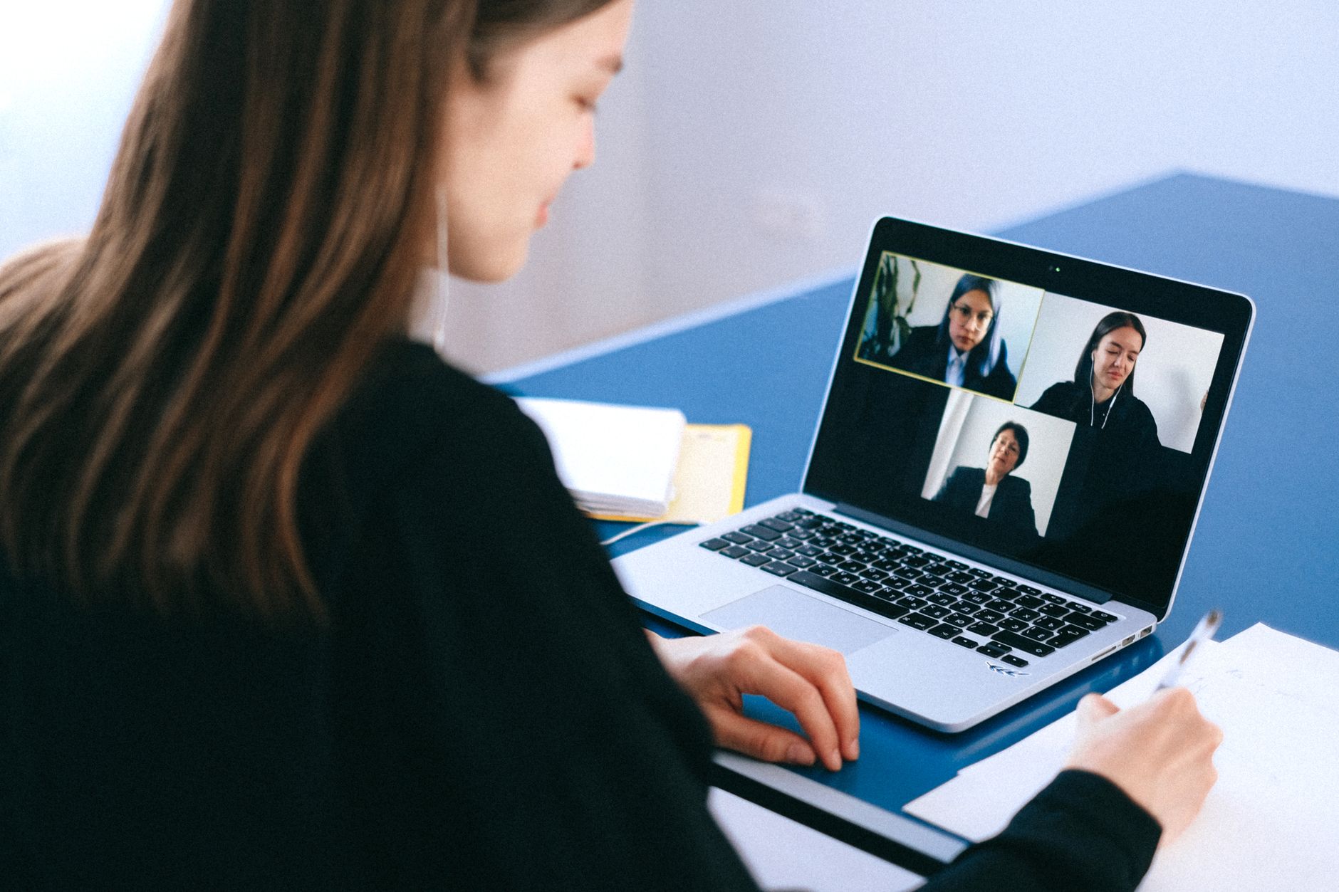 Online-Whiteboards – Frau nimmt am Laptop an einer Videokonferenz teil und macht Notizen
