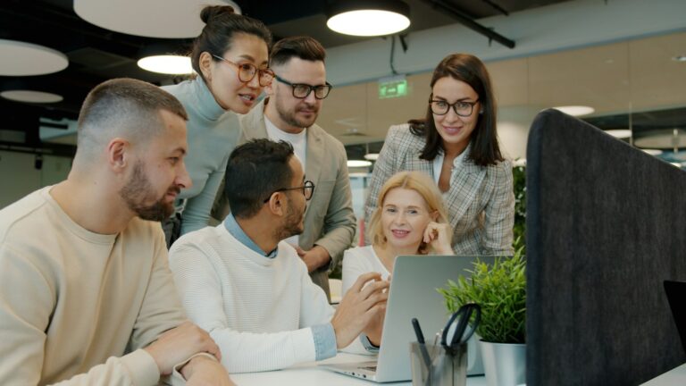 SharePoint vs. OneDrive: Unterschied, Teams-Dateien & Synchronisierung SharePoint vs. OneDrive – Team bespricht gemeinsam Dateien an einem Laptop im Büro