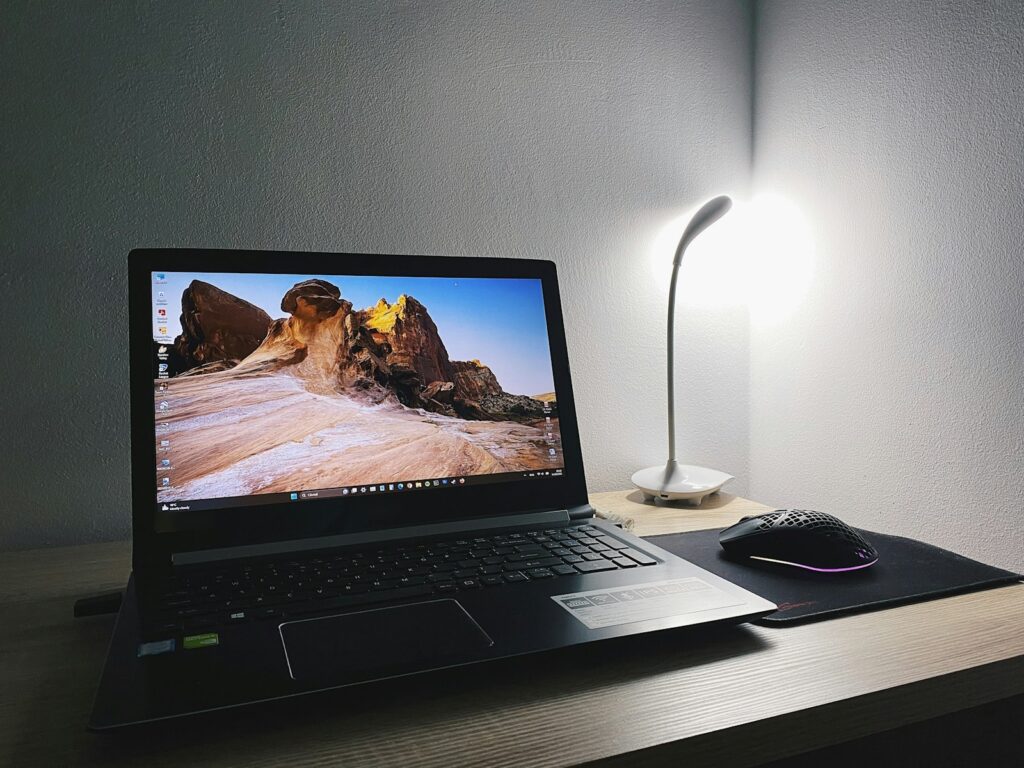 Windows-Laptop auf einem Schreibtisch mit Lampe und Maus, Symbolbild für Sicherheitseinstellungen in Windows