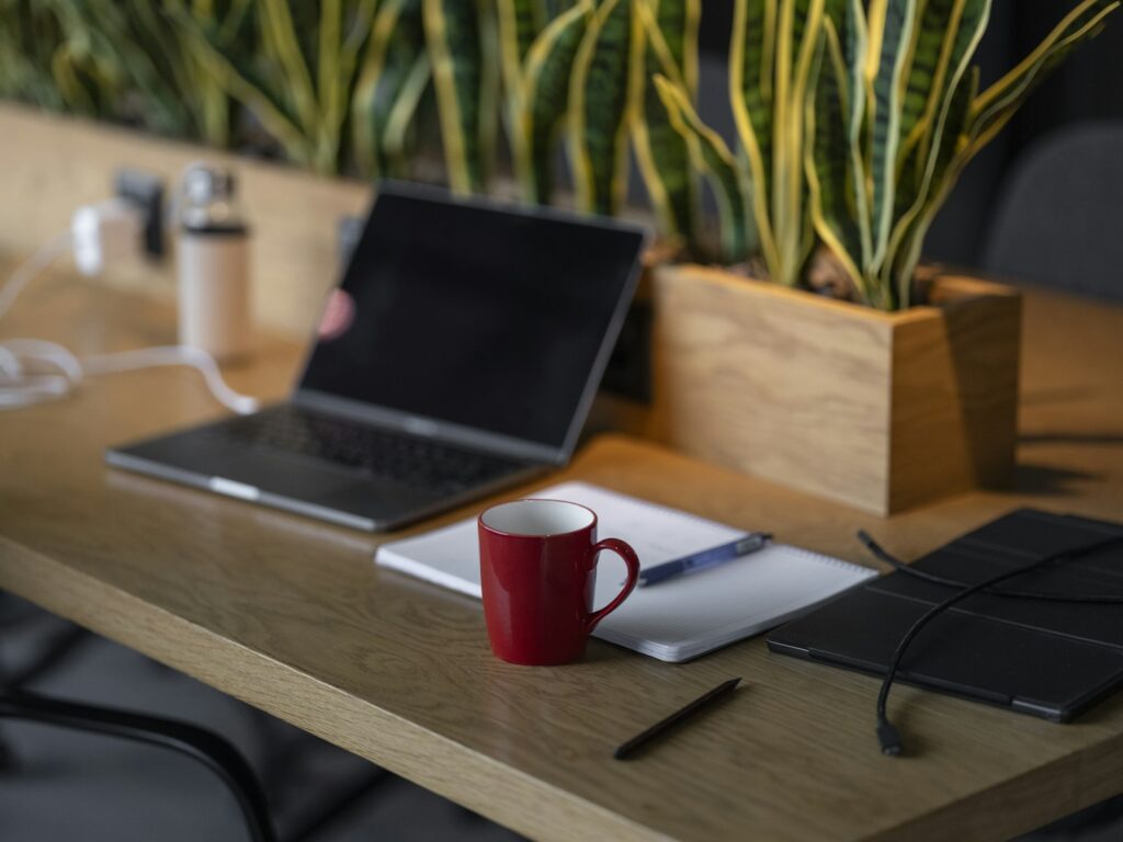 Verlassener Arbeitsplatz mit aufgeklapptem Laptop und roter Tasse – nach einigen Minuten Inaktivität zeigt Teams Abwesend
