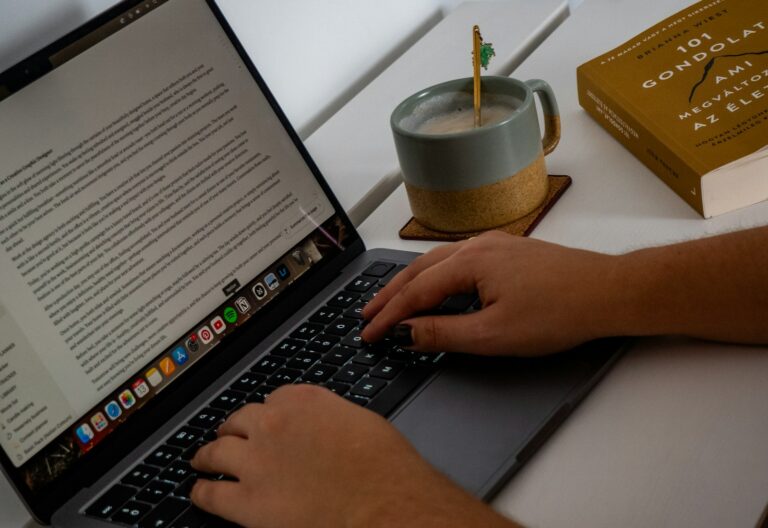 thehometrotters – Hände tippen auf einem Laptop mit geöffnetem Textdokument