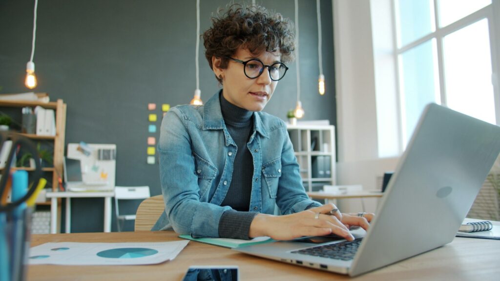 Frau arbeitet im Büro konzentriert am Laptop